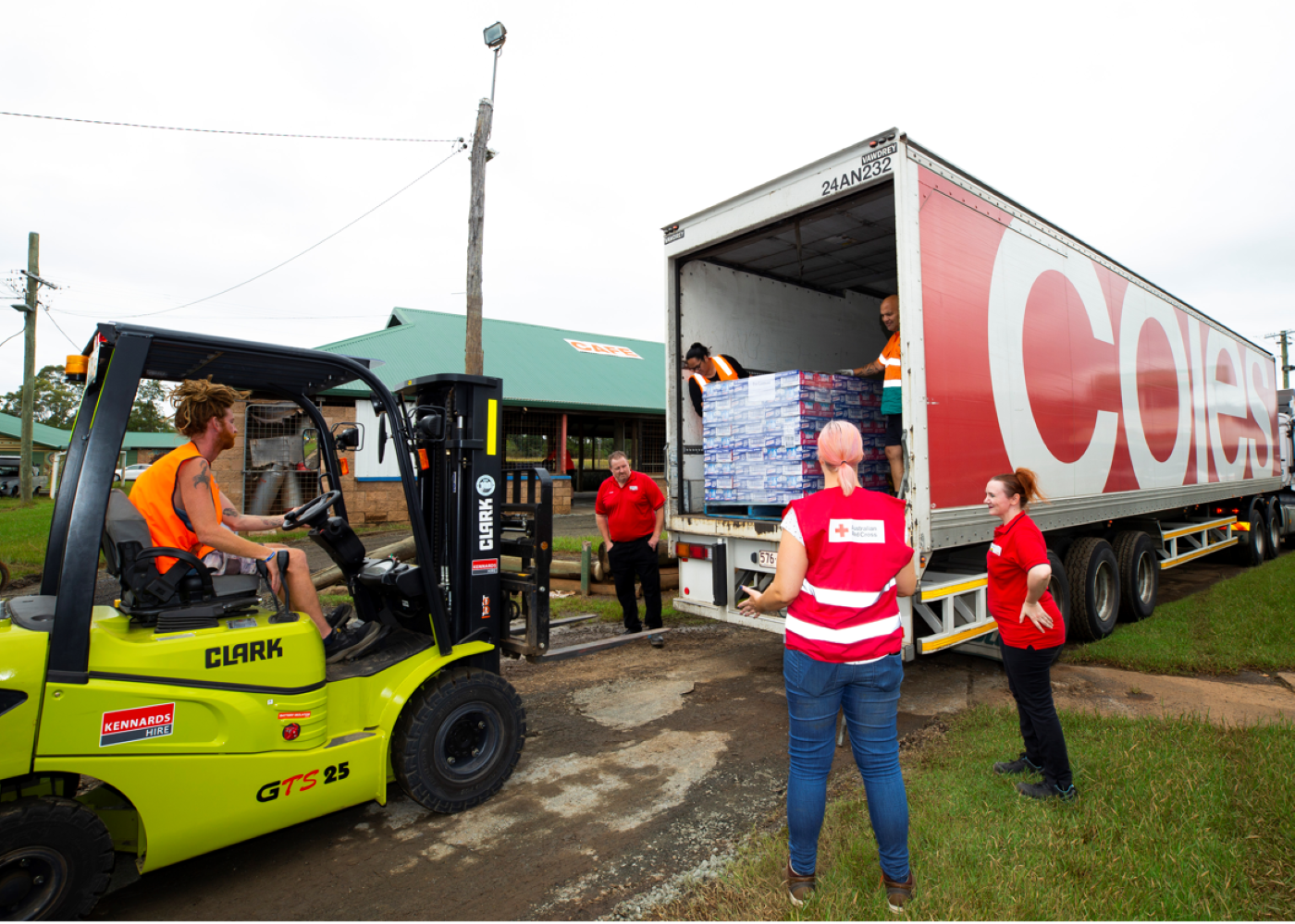 Coles team members and Red Cross volunteers assist in unloading a truckload of essentials